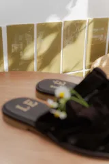 Sandalias tipo mule de cuero color marrón chocolate, con diseño de tiras anchas cruzadas y suela plana.