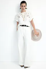 Remera blanca de algodón con cuello redondo y mangas cortas. Presenta un diseño calado en el frente.