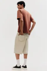 Remera marrón de algodón pesado, corte holgado, cuello redondo ribeteado, hombros caídos y bajo recto.