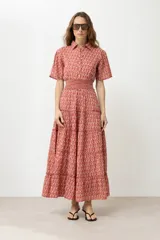 Maxi vestido rojo con estampado de rombos, corte camisero, cuello clásico, mangas cortas abullonadas con puños elásticos, cintura elastizada y falda larga escalonada.