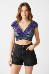 Top corto con estampado floral en tonos violeta, azul y verde, con escote en V profundo y volados en el borde. Elástico en la cintura.