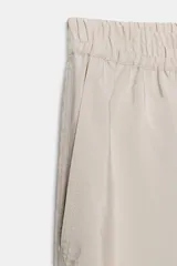 Pantalón ancho color beige de tiro alto con cintura elástica y bolsillos delanteros.