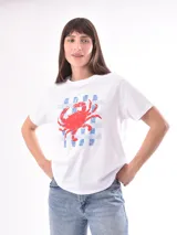 Remera color crudo con estampado de un pez rojo en el frente.