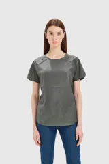 Remera color gris con cuello redondo y mangas cortas con detalle de costuras y calados en los hombros.