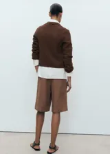 Chaqueta marrón de punto con cuello polo, cierre frontal con botones, dos bolsillos delanteros y mangas largas.
