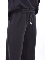 Pantalón de tejido de punto color bordó, de corte ancho y tiro alto con elástico y cordón ajustable en la cintura. Presenta costuras verticales marcadas en el frente de cada pierna.