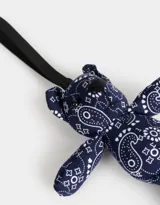 Llavero con forma de oso de peluche azul marino con estampado paisley blanco y cinta de agarre negra.