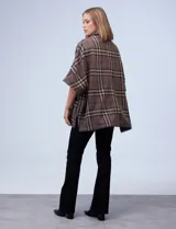 Poncho de tejido soft, marca Weatherproof, con estampado Príncipe de Gales en tonos marrón, beige, azul marino y rojo. Presenta cuello alto con cierre metálico dorado y bolsillos delanteros.