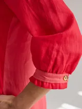 Vestido midi de lino color lila con escote en V y mangas 3/4 abullonadas con puño elástico. Presenta paneles laterales en denim y costuras a la vista en color rojo.