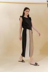 Falda midi de lino y algodón con paneles verticales en color beige, negro y tostado. Diseño portafolio con cruce, abrochada con botones y broches de presión regulables. Detalles desflecados en los cortes verticales y bolsillo escondido en el lateral derecho.