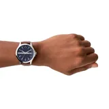 Reloj Armani Exchange modelo Hampton con caja plateada de acero inoxidable, esfera azul con textura y correa de cuero marrón. Incluye indicador de fecha y movimiento de cuarzo. Resistente al agua hasta 50 metros.
