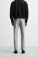 Pantalón negro de corte slim fit, confeccionado en tejido elástico. Cuenta con cintura elástica, bolsillos frontales y traseros de vivo. Cierre frontal con cremallera y botón.