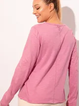 Remera de manga larga color blanco con detalle de bolsillo frontal y cuello con botones metálicos.