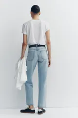Pantalón de jean celeste de tiro alto, corte recto, con cinco bolsillos y cierre frontal con cremallera y botón metálico.