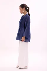 Camisa verde agua con cuello mao, abotonada al frente y mangas largas acampanadas con detalle de pinzas verticales en el frente.