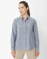 Camisa celeste de manga larga confeccionada en algodón chambray, con cuello clásico, cierre frontal con botones, dos bolsillos de parche en el pecho y corte relajado.