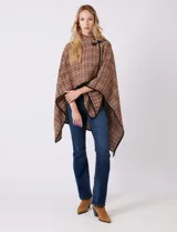 Ruana tejida de la marca Jones New York, con estampado a cuadros en tonos marrón, beige y blanco. Presenta cuello alto y cierre frontal con botón trenca y botón a presión interno. Los bordes están ribeteados en negro.