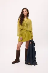 Vestido corto color verde lima, estilo camisero, confeccionado en chiffon transparente. Tiene cuello camisero, mangas largas abullonadas y elástico en la cintura.