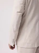 Saco de lino color beige con rayas verticales, solapa de muesca, cierre de dos botones, tres bolsillos frontales y puños con cuatro botones.