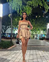 Vestido corto color dorado, con breteles finos, corte ajustado y falda con volados.