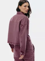 Chaqueta corta de denim color borgoña con cuello clásico, cierre frontal con botones metálicos y bolsillos de parche en el pecho.