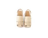 Sandalia de cuero trenzado color hueso, con punta cuadrada, talón abierto, pulsera ajustable con hebilla metálica y taco ancho forrado en cuero.