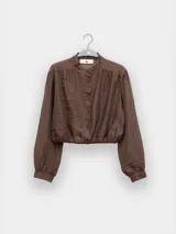 Blusa corta celeste de tejido arrugado liviano, con cuello mao, botones al frente, mangas abullonadas y ruedo elastizado.