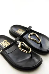 Sandalias de cuero color marrón con base plana y tira ancha sobre el empeine con hebilla dorada.