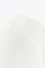 Remera blanca de punto liso, corte amplio, cuello redondo y manga corta.