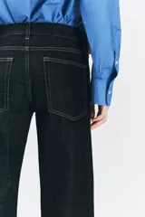 Jeans de tiro bajo con cintura con trabillas, cinco bolsillos, pespuntes marcados a contraste y pierna ancha.