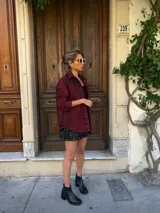 Camisa de denim color borgoña con efecto lavado, corte holgado, cuello clásico y cierre frontal con botones dorados.