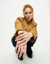 Anillo plateado con un cristal facetado verde en forma de lágrima.