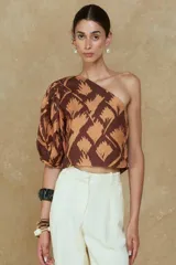 Top marrón con estampado de hojas color naranja, de un solo hombro y manga corta abullonada.