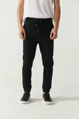 Pantalón de jogging negro con puños ajustados y cordón en la cintura. Confeccionado en algodón y poliéster, con logo estampado en la pierna izquierda.