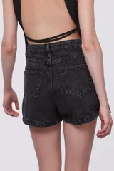 Short de jean negro con efecto lavado, tiro alto, corte ajustado y diseño cruzado con cierre de botón.
