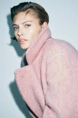 Abrigo amplio color rosa, confeccionado en hilatura con lana y alpaca. Tiene cuello solapa, manga larga, forro interior y cierre frontal con gancho metálico.