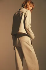 Chaqueta color beige de cuello solapa y manga larga con hombreras acabada en puño. Presenta bolsillos laterales y falso bolsillo de vivo en pecho. Cierre frontal con botones.