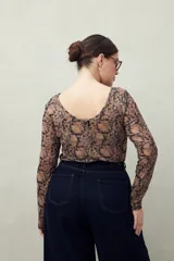 Top de manga larga en tejido translúcido con estampado animal print en tonos marrones y negros. Diseño ajustado con transparencia.