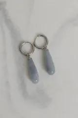 Par de aros colgantes con argolla de acero quirúrgico hipoalergénico y dije en forma de gota de piedra natural color marrón.