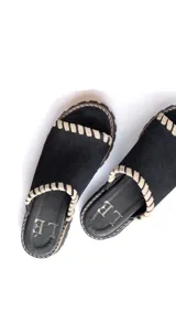 Chancla tipo mule de gamuza color beige, con puntera abierta y suela track gruesa. Presenta pespuntes decorativos en color claro alrededor del borde superior y en la unión de la capellada con la suela.