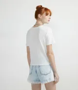 Blusa blanca de viscosa texturizada, corte crop, cuello redondo y manga corta.