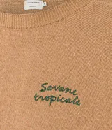 Remera de manga corta color marrón claro, con cuello redondo y ribete en puños y ruedo. Presenta un bordado con la frase "Savane tropicale" en el pecho.