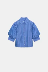 Camisa celeste con rayas verticales blancas, cuello clásico, manga 3/4 abullonada y cierre frontal con botones.