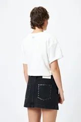 Minifalda de jean celeste con tiro bajo y detalle de tachas metálicas en los bolsillos.
