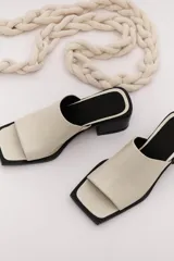 Sandalia marrón de cuero con punta cuadrada, talón abierto y faja ancha. Tiene detalle de elástico oculto en la cara interna de la capellada. El forro y la plantilla son de cuero vacuno.