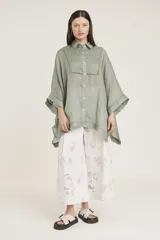 Camisa blanca de lino con corte amplio, cuello camisero y mangas 3/4 con detalle de puntilla en el borde.