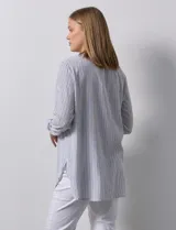 Blusa de gasa bambula a rayas verticales celestes y blancas, con cuello a la base, escote en V con botones y bordado floral negro. Mangas largas regulables con presilla y botón.