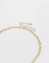 Collar corto dorado con cadena de eslabones y dijes colgantes de corazones, tréboles, letras y piedras rojas.
