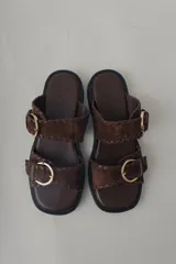 Sandalias de plataforma color verde militar, confeccionadas en cuero, con doble tira ancha con hebillas doradas y suela de goma negra.