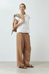 Remera color crudo con bordado de flores en el ruedo y mangas cortas.